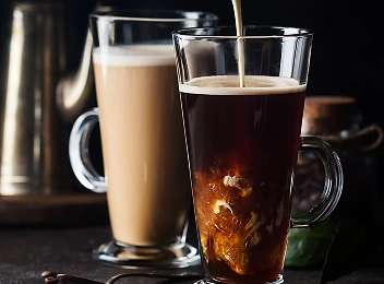 Crème fraîche versée dans un verre de café noir dans un cadre de café sophistiqué.