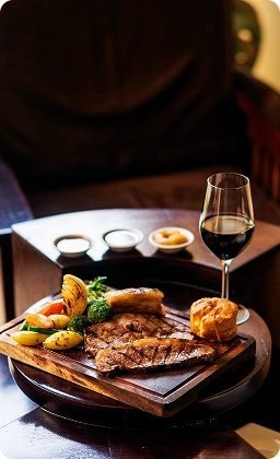 Steak grillé tranché servi avec de l'ail rôti, du pain et des plats d'accompagnement dans un cadre de restaurant.