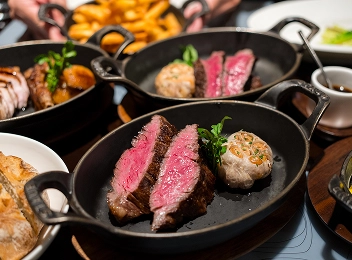 Steak grillé avec des légumes rôtis servi sur une planche en bois avec un verre de vin rouge.