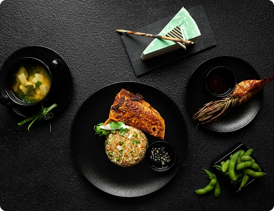 Repas de style japonais avec saumon grillé, riz frit, soupe miso, crevettes et edamame.