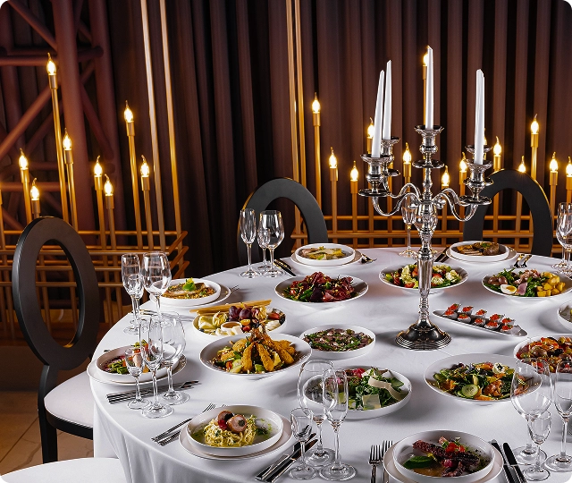 Table de banquet somptueuse remplie de plats gastronomiques, de salades et de décorations de bougies élégantes.